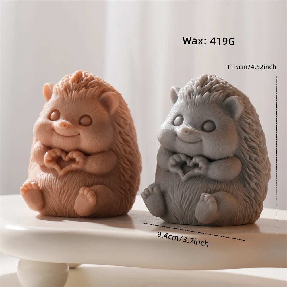Two hedgehog-shaped figurines, one brown and one gray, on a white surface with measurements displayed.