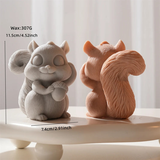 Two ceramic squirrel figurines, one gray and one brown, on a white surface with a light background.